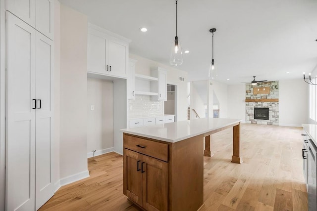 16470 W 166th Pl, Olathe, KS 66062 - kitchen with a fireplace, light wood-type flooring, a center island, open shelves, and baseboards