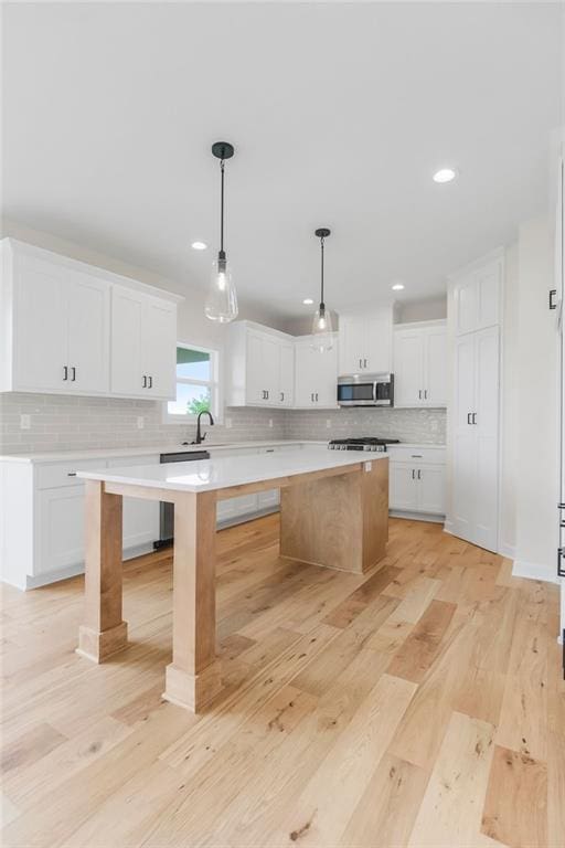 16470 W 166th Pl, Olathe, KS 66062 - kitchen with stainless steel microwave, a kitchen island, light countertops, decorative backsplash, and white cabinetry