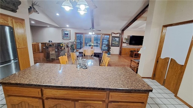 2101A Dove Rd, Longton, KS 67352 - kitchen with vaulted ceiling, ceiling fan with notable chandelier, a kitchen island, light tile patterned flooring, and freestanding refrigerator