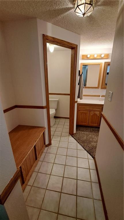 2101A Dove Rd, Longton, KS 67352 - bathroom featuring toilet, vanity, tile patterned floors, and a textured ceiling