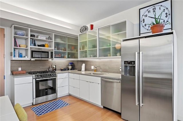 912 Baltimore Ave Unit 802, Kansas City, MO 64105 - kitchen featuring stainless steel appliances, white cabinetry, backsplash, and light wood-type flooring