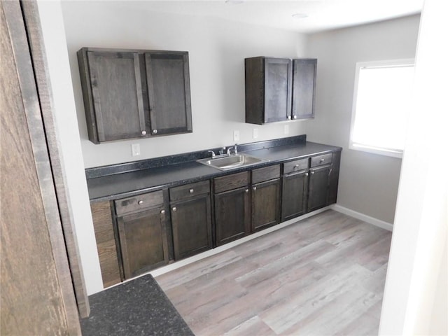 308 W 5th St, Pittsburg, KS 66762 - kitchen featuring baseboards, dark countertops, dark brown cabinets, a sink, and light wood-type flooring
