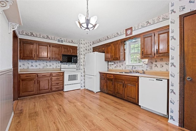 14404 Kansas Ave, Bonner Springs, KS 66012 - kitchen with white appliances, wallpapered walls, a chandelier, light wood-style flooring, and light countertops