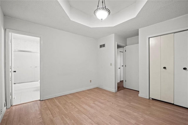 14404 Kansas Ave, Bonner Springs, KS 66012 - unfurnished bedroom featuring light wood-type flooring, ensuite bath, a closet, and a textured ceiling