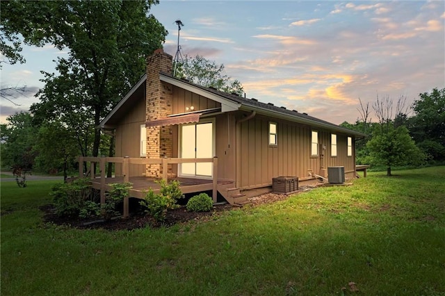 14404 Kansas Ave, Bonner Springs, KS 66012 - view of side of property with board and batten siding, a wooden deck, a chimney, and a yard