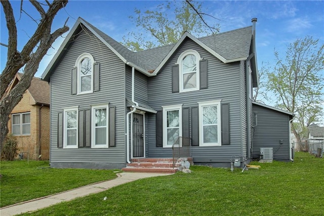 traditional-style house featuring central AC, a front lawn, roof with shingles, and entry steps