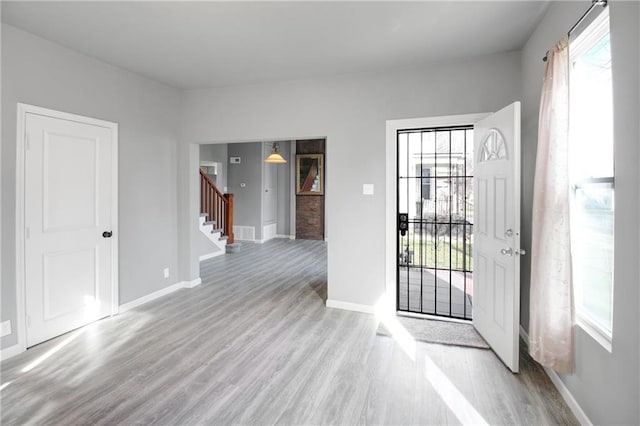 foyer entrance with light wood-style flooring, baseboards, and stairway