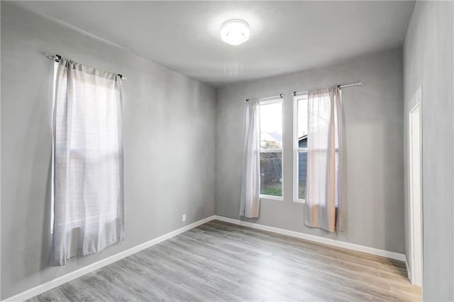 spare room featuring baseboards and wood finished floors