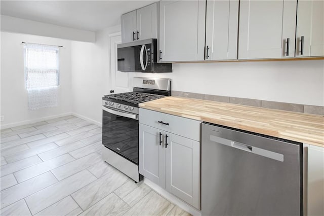 kitchen featuring wooden counters, baseboards, and appliances with stainless steel finishes