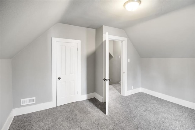 additional living space with baseboards, visible vents, carpet flooring, and vaulted ceiling