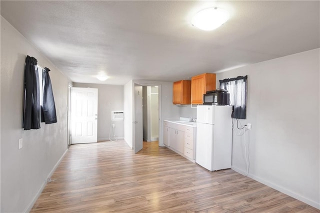 kitchen featuring freestanding refrigerator, baseboards, black microwave, and light wood finished floors