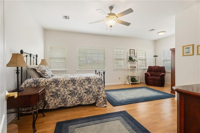 bedroom with baseboards, wood finished floors, visible vents, and a ceiling fan