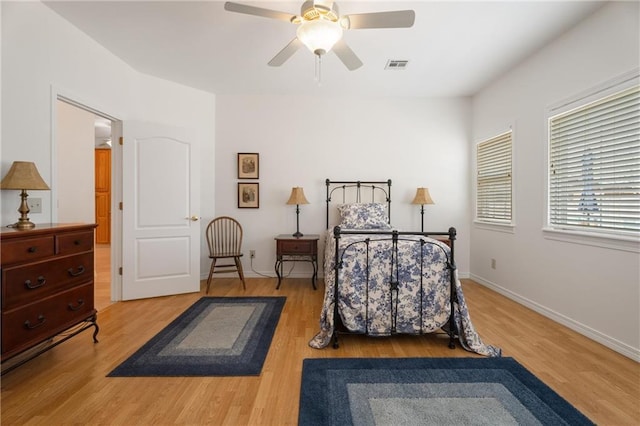 bedroom with baseboards, wood finished floors, visible vents, and a ceiling fan