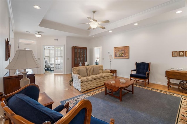 living room with a ceiling fan, wood finished floors, a raised ceiling, baseboards, and recessed lighting