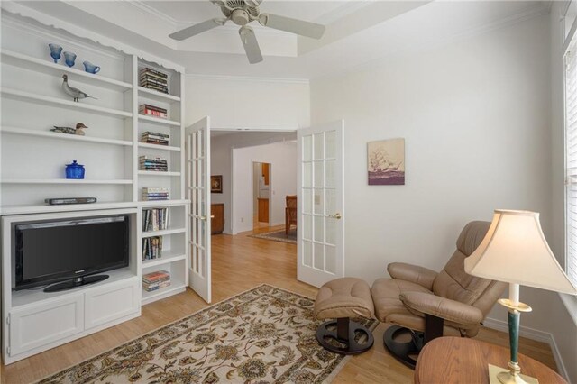 living area with light wood finished floors, french doors, a ceiling fan, and crown molding