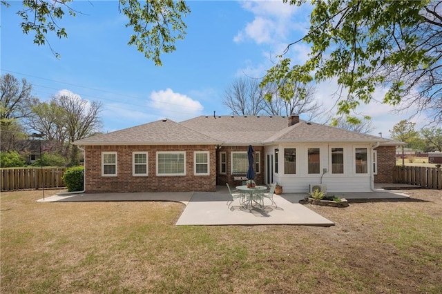 rear view of property featuring a patio area, a fenced backyard, brick siding, and a yard