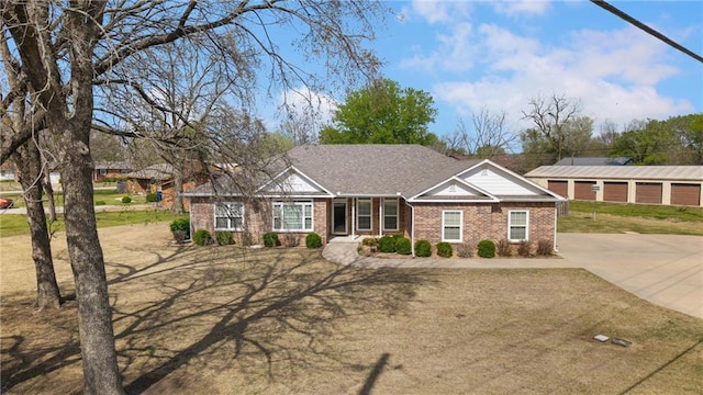 view of front of home with brick siding, driveway, and a shingled roof