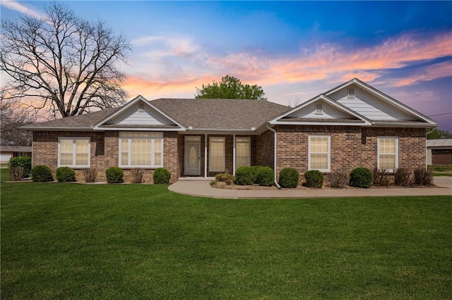 ranch-style home featuring brick siding and a yard