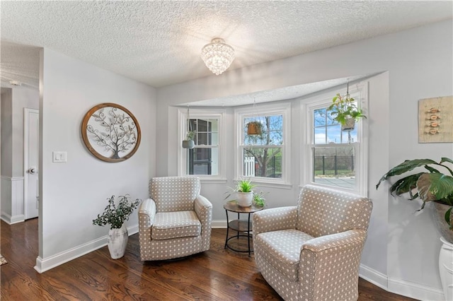 living area featuring a textured ceiling, baseboards, wood finished floors, and a chandelier