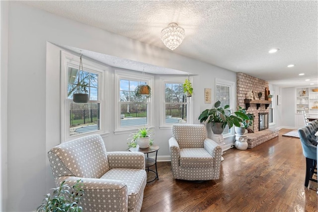 living area featuring a textured ceiling, wood finished floors, and a fireplace