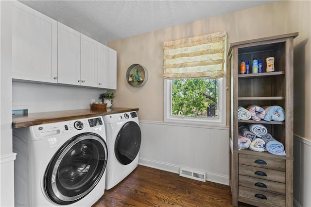 washroom with visible vents, dark wood-style flooring, a textured ceiling, washing machine and clothes dryer, and cabinet space
