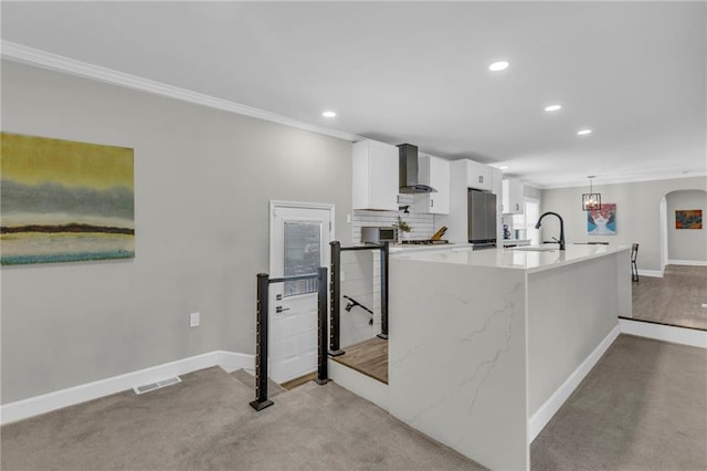 kitchen with wall chimney range hood, freestanding refrigerator, recessed lighting, a sink, and baseboards