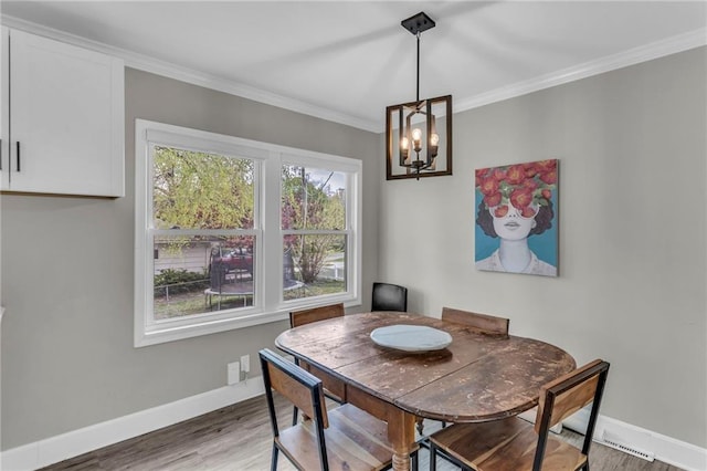 dining area featuring baseboards, a chandelier, wood finished floors, and crown molding