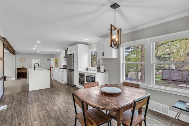 dining space with crown molding, wood finished floors, baseboards, and recessed lighting