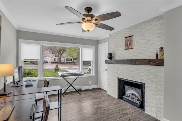 office space featuring ceiling fan, baseboards, wood finished floors, a fireplace, and ornamental molding