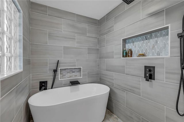 full bath with a soaking tub, tile walls, a tile shower, and healthy amount of natural light