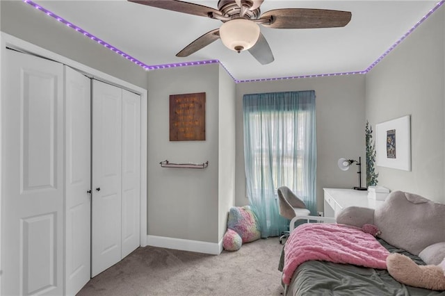carpeted bedroom with a closet, baseboards, and ceiling fan
