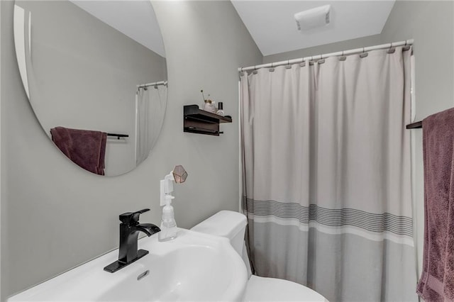 bathroom featuring toilet, a sink, lofted ceiling, and curtained shower