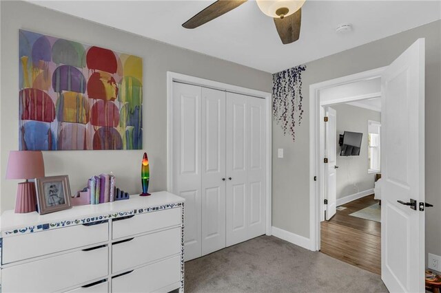 carpeted bedroom with a closet, baseboards, and a ceiling fan