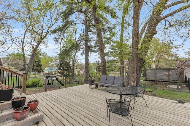wooden terrace featuring a playground, outdoor dining area, and an outdoor fire pit