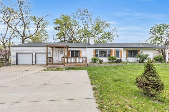 view of front facade featuring a garage, a chimney, a front yard, and driveway