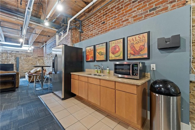 308 W 8th St Unit 505, Kansas City, MO 64105 - kitchen featuring light countertops, a sink, brick wall, and appliances with stainless steel finishes