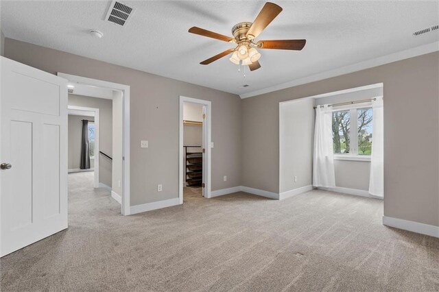 200 NW 180th St, Smithville, MO 64089 - unfurnished bedroom with light colored carpet, baseboards, a spacious closet, a textured ceiling, and a ceiling fan