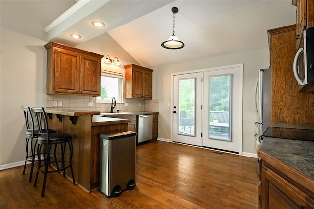 1216 SE Meridian Dr, Lees Summit, MO 64081 - kitchen featuring appliances with stainless steel finishes, a breakfast bar area, baseboards, decorative backsplash, and vaulted ceiling