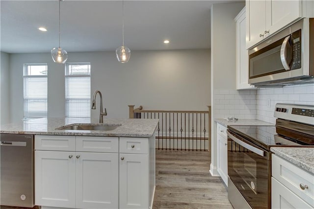 kitchen featuring tasteful backsplash, a sink, light wood-style floors, white cabinets, and appliances with stainless steel finishes