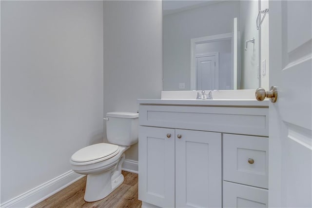 bathroom featuring toilet, vanity, baseboards, and wood finished floors