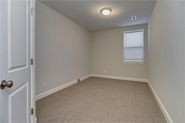 carpeted spare room featuring baseboards, visible vents, and a textured ceiling