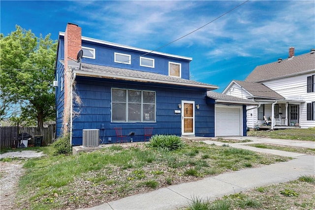 view of front of house featuring fence, a chimney, cooling unit, and a garage