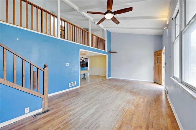 unfurnished living room featuring beam ceiling, visible vents, a ceiling fan, stairway, and wood-type flooring