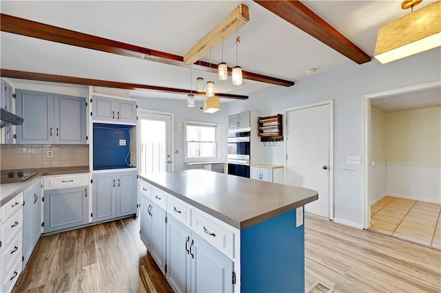 kitchen with black electric cooktop, light wood-style floors, stainless steel double oven, and beam ceiling