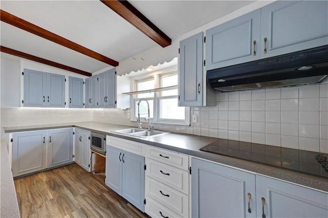 kitchen featuring a sink, stainless steel microwave, backsplash, black electric stovetop, and under cabinet range hood