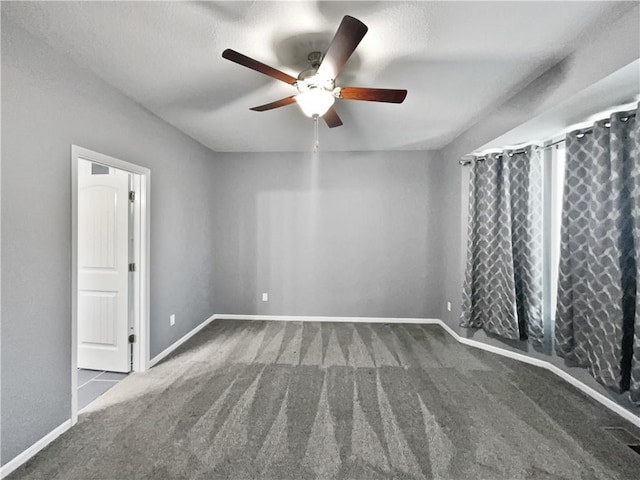 carpeted spare room with baseboards and ceiling fan