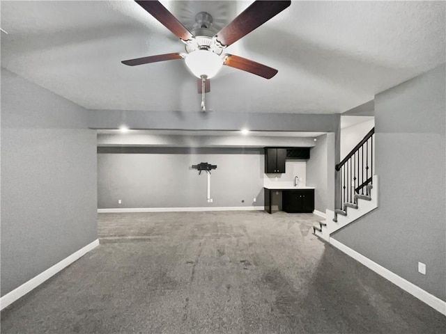 unfurnished living room with stairs, carpet floors, a sink, baseboards, and ceiling fan