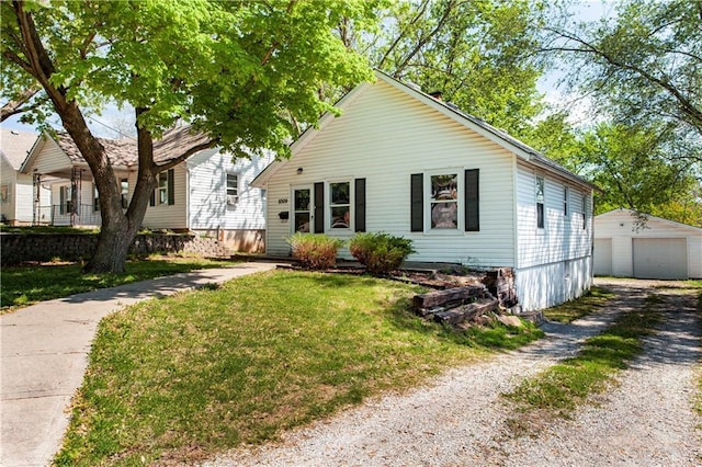 bungalow-style home with a front yard, an outbuilding, a garage, and driveway