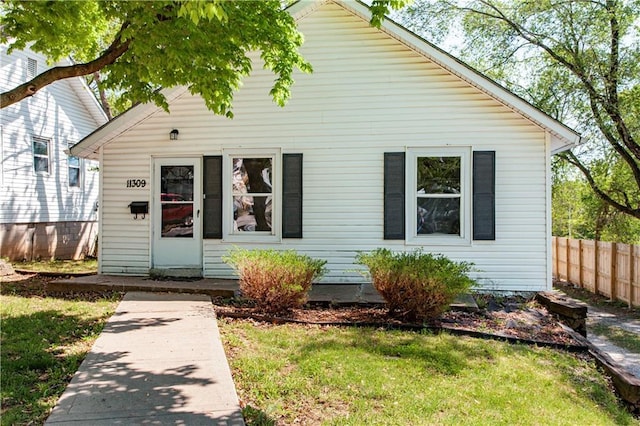 bungalow featuring fence and a front lawn
