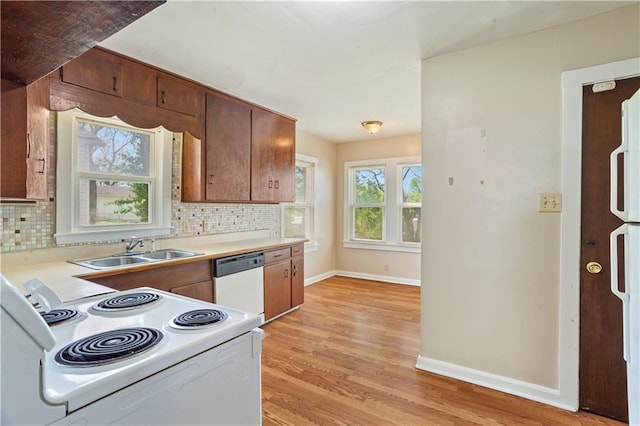kitchen featuring a sink, white appliances, baseboards, backsplash, and light wood-style floors